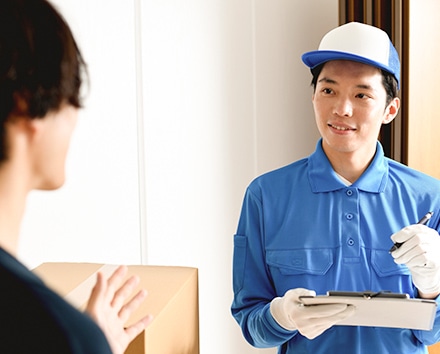 不用品回収・買取の作業スタッフがお客様の玄関で書類を確認している様子